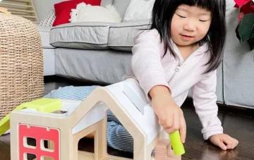 Child playing with peg people on the Modular Playhouse from The Observer Play Kit